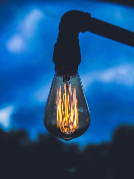 Close-up de lâmpada iluminada contra o céu azul