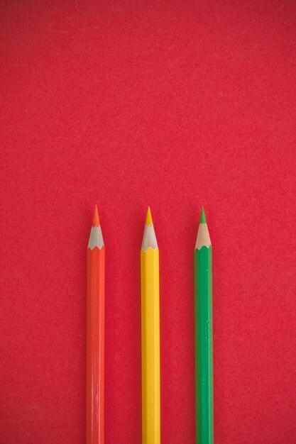 Foto close-up de lápis multicoloridos contra fundo vermelho
