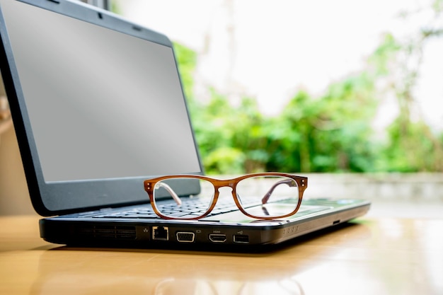 Foto close-up de laptop e óculos na mesa