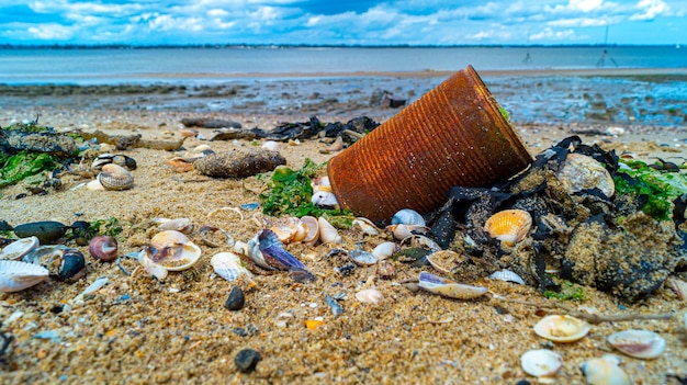 Foto close up de latas enferrujadas desgastadas na praia poluição de areia lixo no oceano