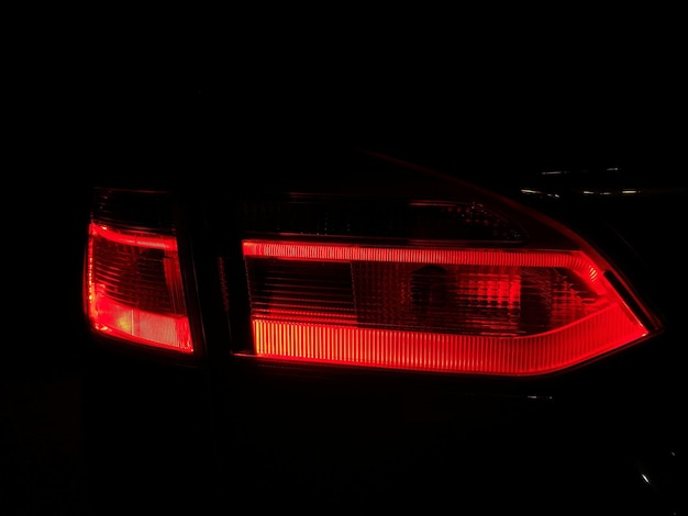 Close-up de luz traseira vermelha iluminada de carro à noite