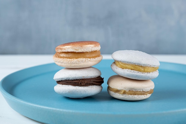 Close Up de macarons com recheio de ganache de chocolate e doce de leite empilhado em um prato azul