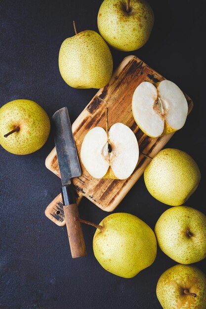 Foto close-up de maçãs de granny smith e faca na tábua de cortar sobre a mesa