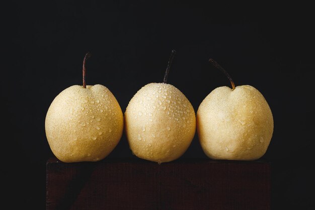 Foto close-up de maçãs molhadas em mesa de madeira contra fundo preto