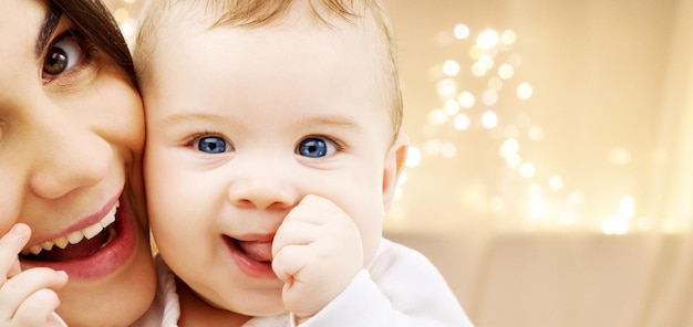 Close-up de mãe com bebê sobre luzes de Natal