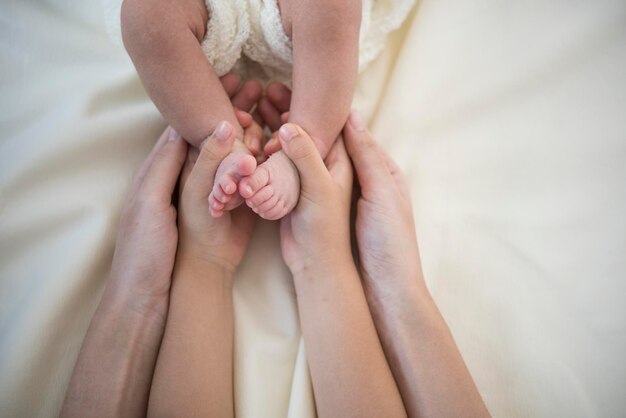 Close-up de mãe e pai segurando as pernas na cama