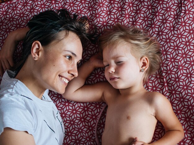 Foto close-up de mãe sorridente olhando para a filha na cama