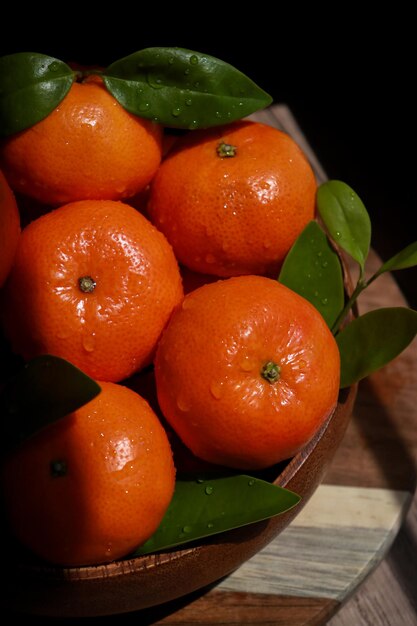 close-up de mandarins com folhas em uma tigela de madeira