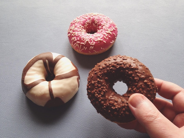 Close-up de mão cortada segurando um donut na mesa
