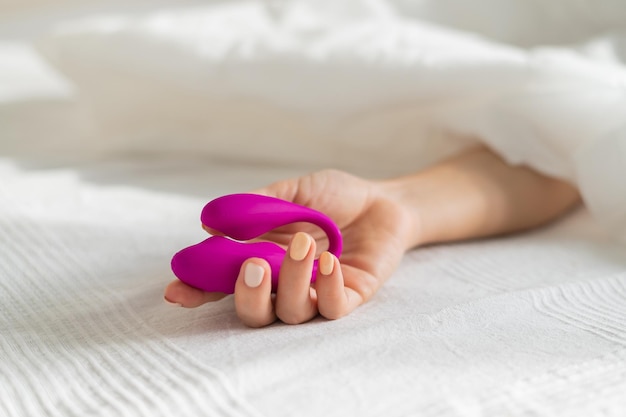 Close-up de mão de mulher com pétalas cor-de-rosa na cama