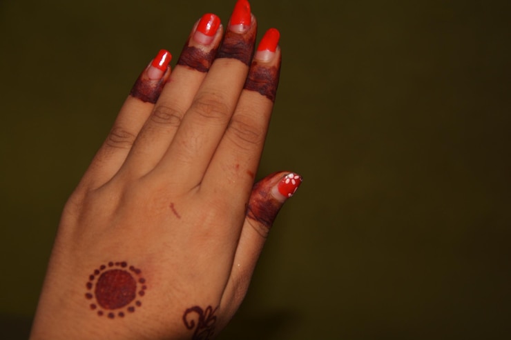 Foto close-up de mão de mulher com tatuagem de henna contra fundo colorido