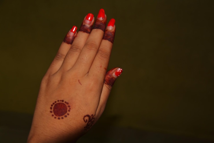 Foto close-up de mão de mulher com tatuagem de henna contra fundo colorido