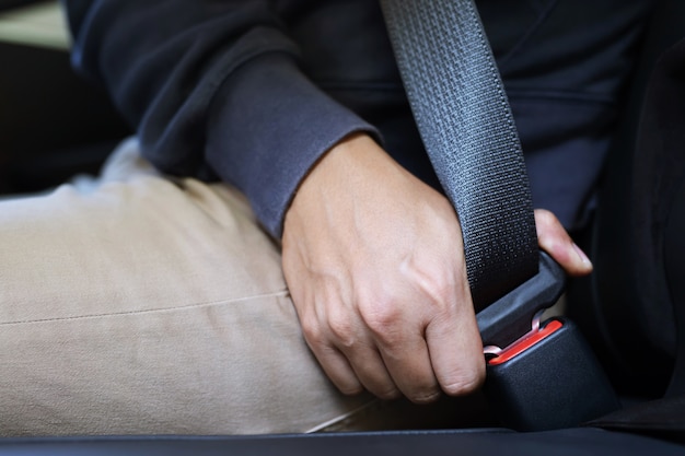 Close up de mão de pessoas que prende o cinto de segurança no carro para segurança antes de dirigir na estrada