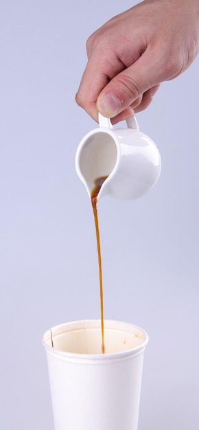 Foto close-up de mão derramando xícara de café contra fundo branco