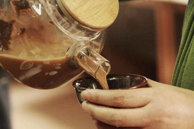 Foto close-up de mão derramando xícara de café