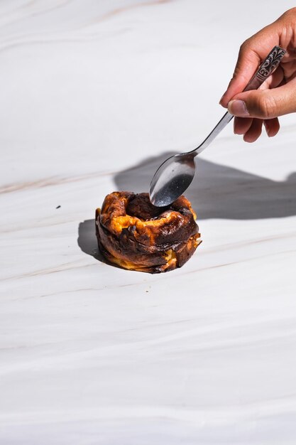 Foto close-up de mão feminina comendo bolo de queijo basco san sebastian queimado