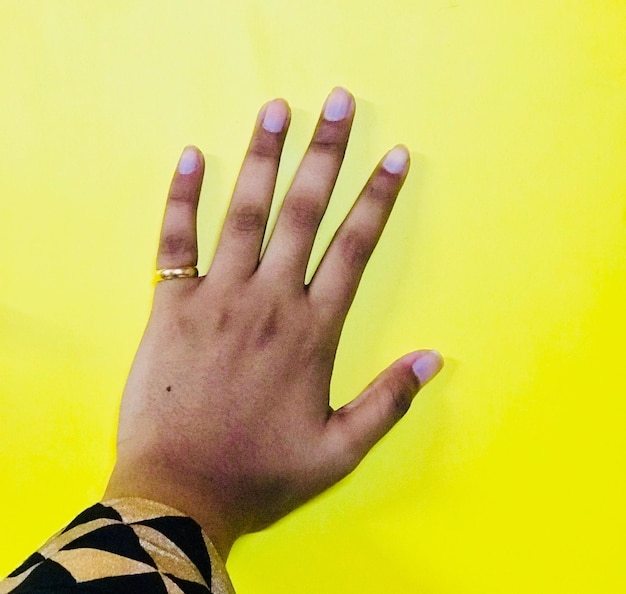 Foto close-up de mão humana contra fundo amarelo
