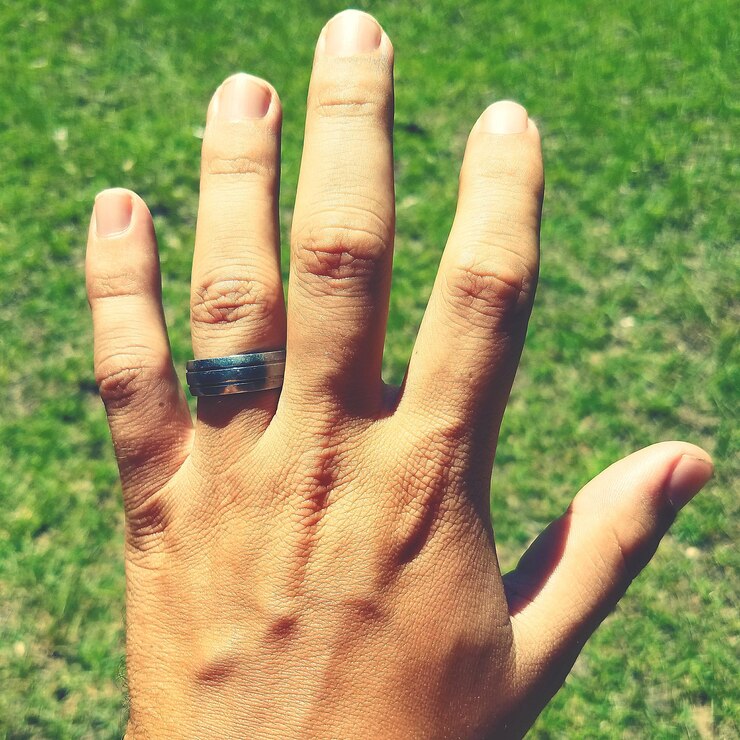 Foto close-up de mão masculina no campo com anel de casamento