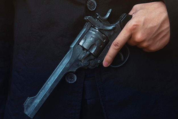 Foto close-up de mão segurando arma em fundo preto