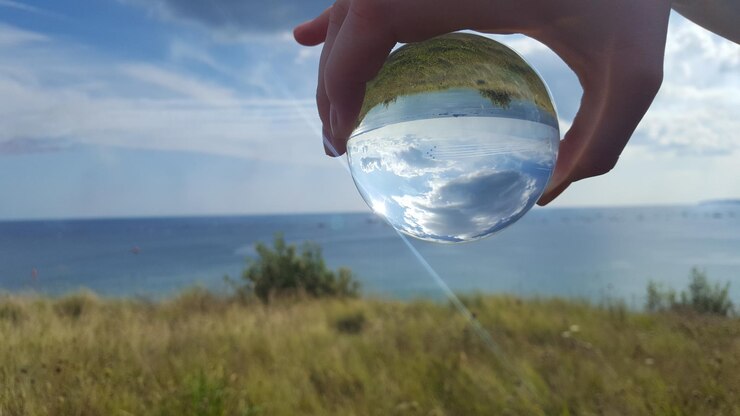 Foto close-up de mão segurando bola de cristal contra o céu