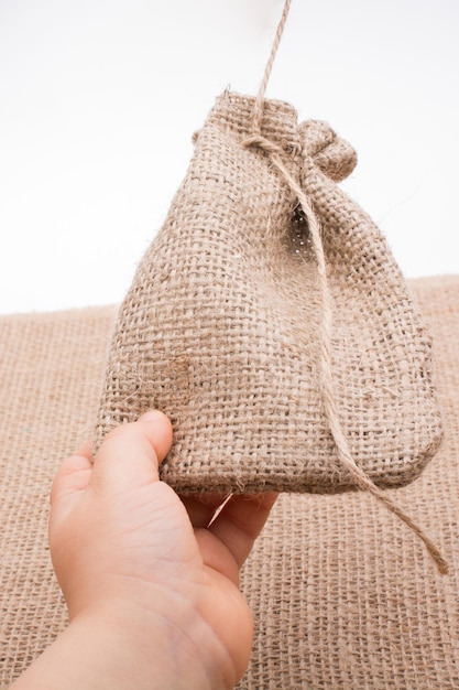 Foto close-up de mão segurando bolsa de yute contra fundo branco