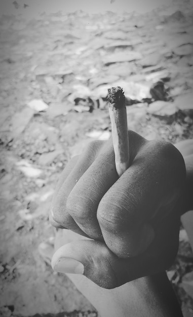 Foto close-up de mão segurando cigarro na praia