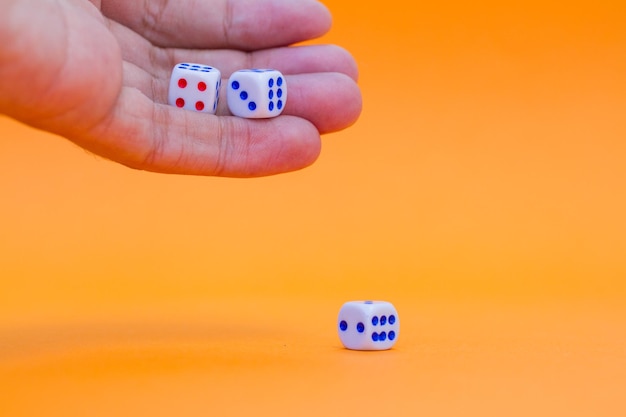 Foto close-up de mão segurando dados em fundo laranja