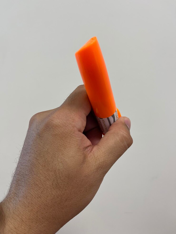 Foto close-up de mão segurando laranja contra fundo branco