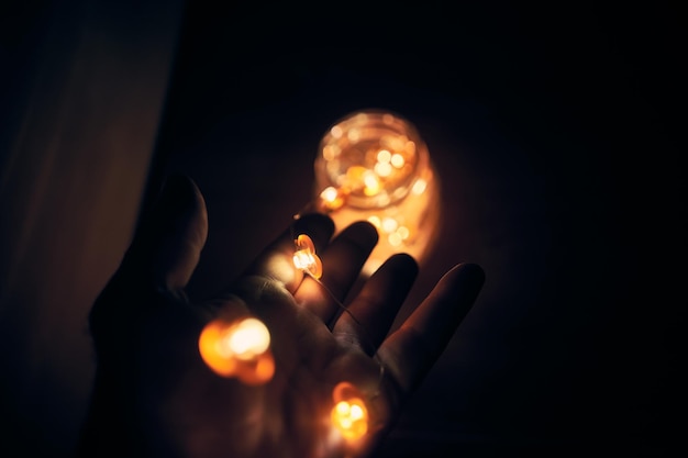 Close-up de mão segurando luzes iluminadas em frasco na mesa
