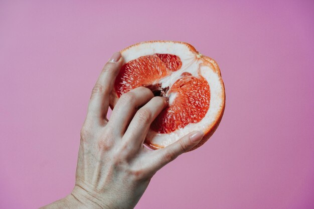 Foto close-up de mão segurando maçã contra fundo rosa