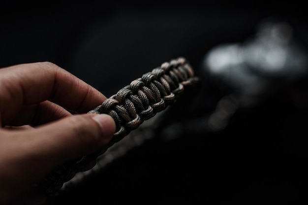 Close-up de mão segurando metal contra fundo preto