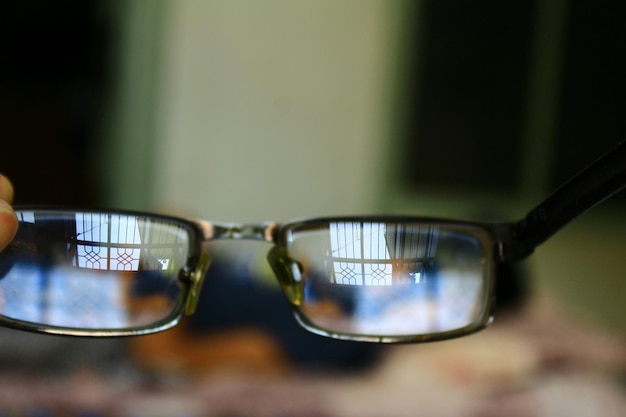 Foto close-up de mão segurando óculos contra fundo desfocado