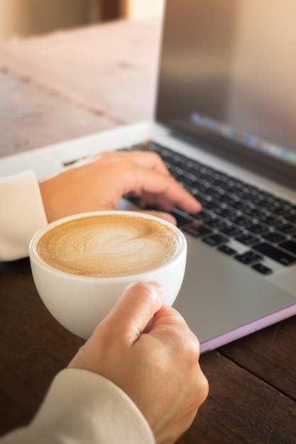 Foto close-up de mão segurando xícara de café na mesa em casa