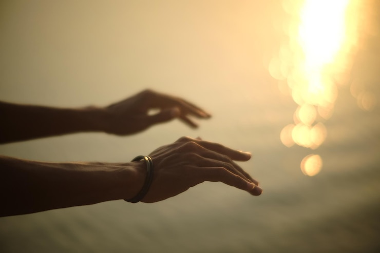 Foto close-up de mãos contra o céu durante o pôr do sol