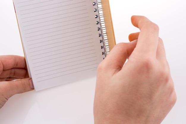 Foto close-up de mãos cortadas segurando um caderno em espiral em fundo branco