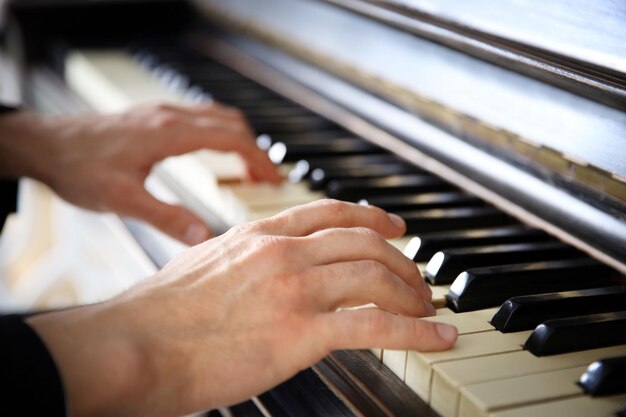 Close-up de mãos de homem tocando piano clássico