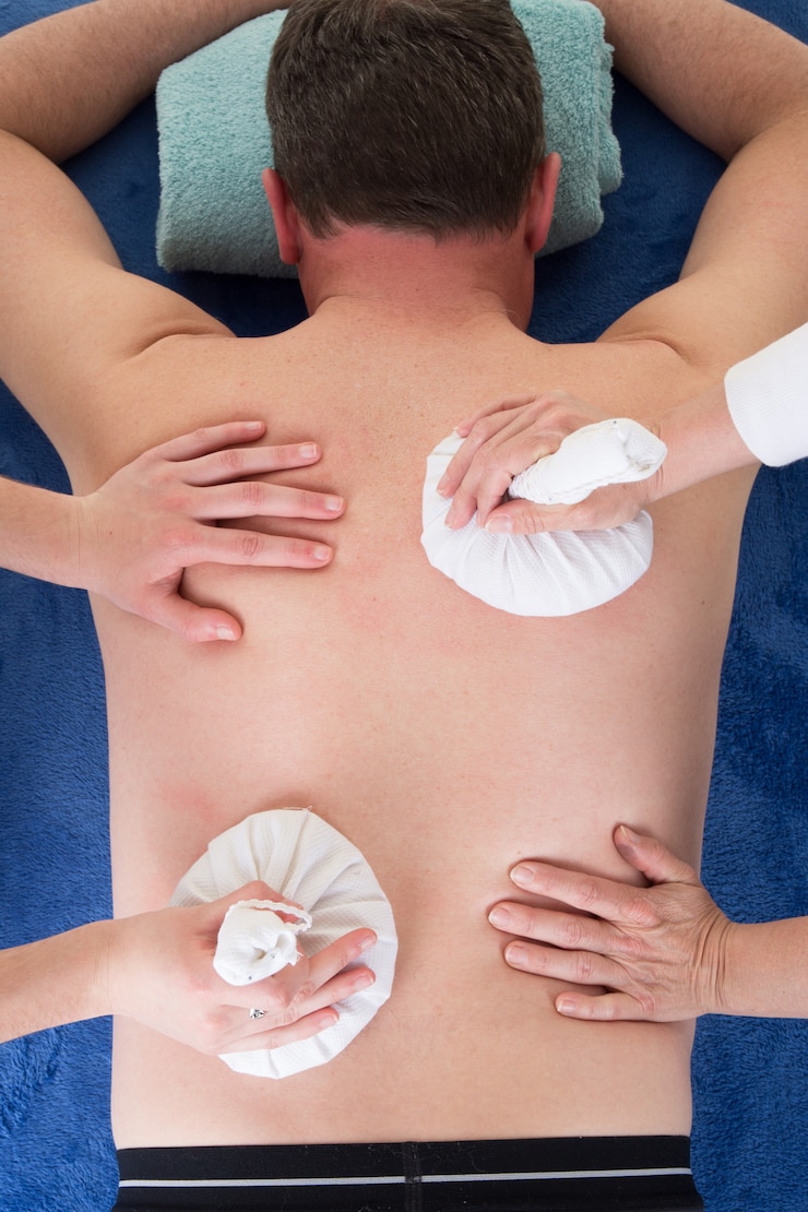 Foto close-up de mãos de massagem feminina dar ervas bola terapia quente para homem
