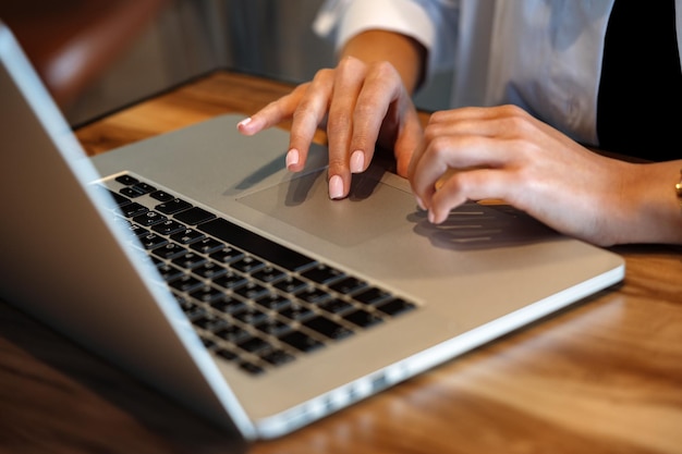 Close-up de mãos de mulher digitando no laptop no café
