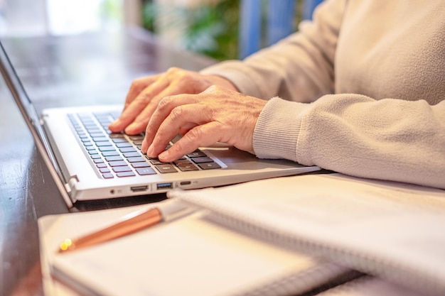 Close-up de mãos de mulheres digitando no laptop enquanto trabalham ou estudam desfrutando da atividade de ensino