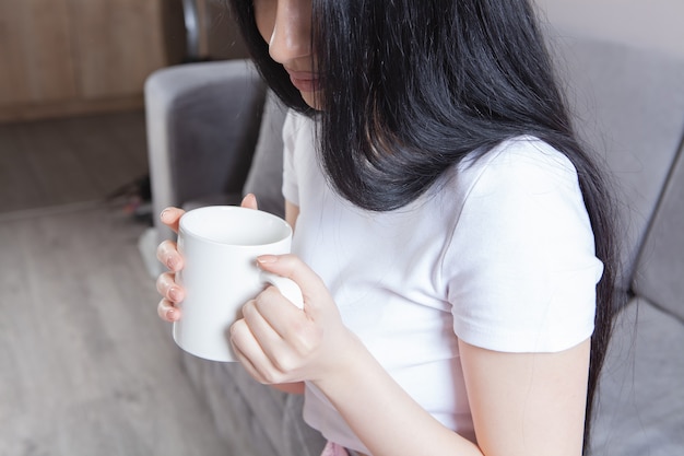 Close-up de mãos femininas com uma caneca de bebida.