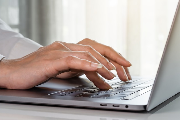 Close-up de mãos femininas de mulher de negócios digitando em um teclado de laptop