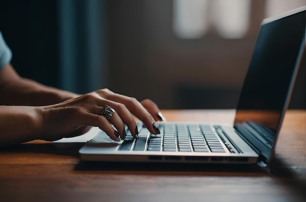 Foto close-up de mãos femininas digitando no teclado do laptop em uma mesa de madeira