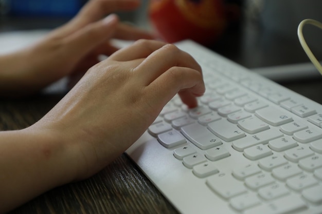 Close-up de mãos femininas digitando no teclado no escritório em casa