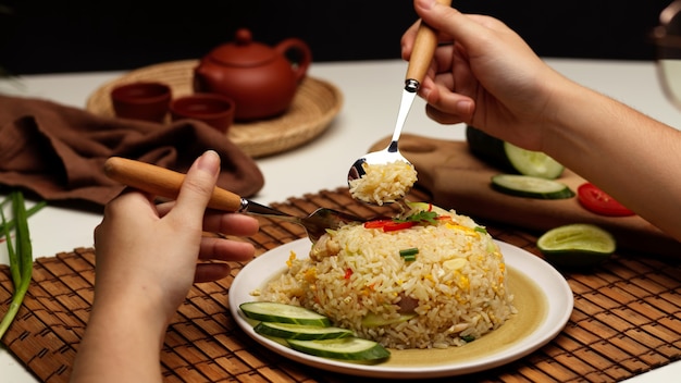 Close-up de mãos femininas segurando talheres para comer arroz frito tailandês em restaurante