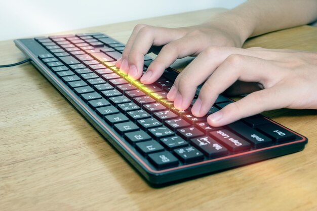 Close-up de mãos masculinas digitando no teclado preto empresário trabalhando com efeito de luz conceitual