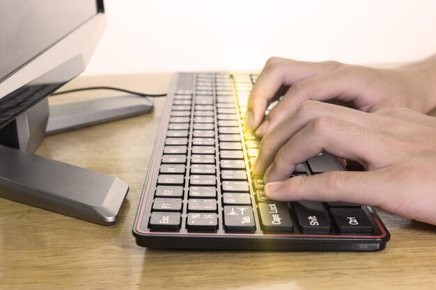 Foto close-up de mãos masculinas digitando no teclado preto empresário trabalhando com efeito de luz conceitual