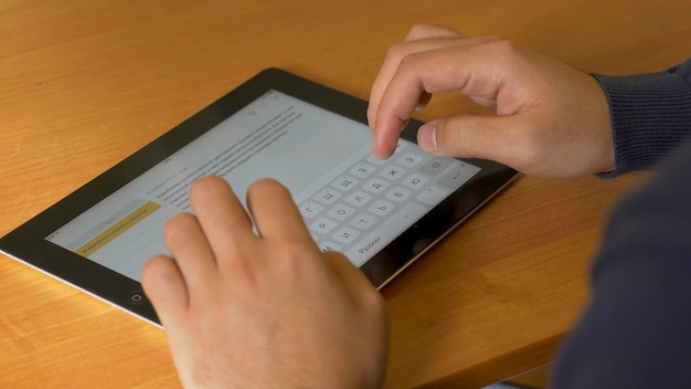 Close-up de mãos masculinas usando tablet digital moderno e computador no escritório vista frontal de um empresário