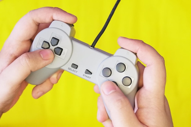 Foto close-up de mãos segurando o controlador de jogo contra fundo amarelo