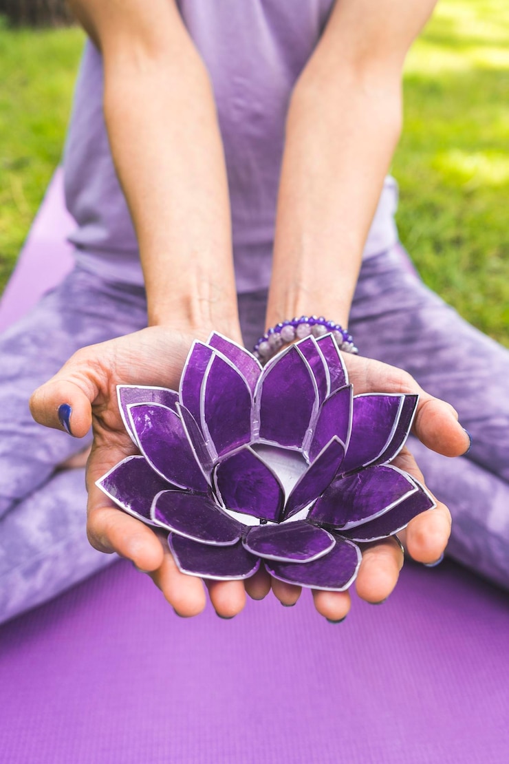 Foto close up de mãos segurando um lótus de vidro roxo conceito de ioga e meditação tiro vertical