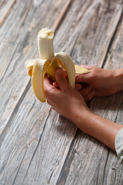 Foto close-up de mãos segurando uma banana aberta estilo de vida saudável e conceito de nutrição